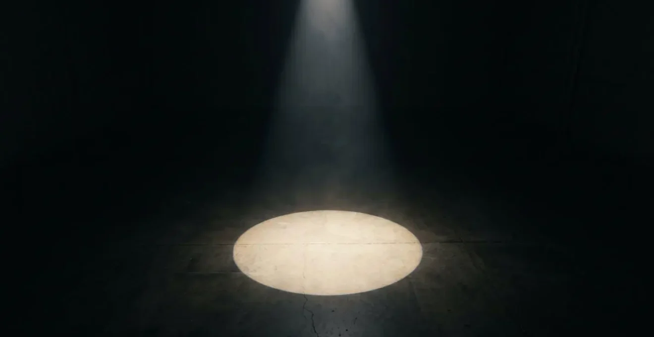 A single spotlight illuminating a small circle on a dark, empty floor, symbolizing a dark launch that targets a small user segment invisibly.