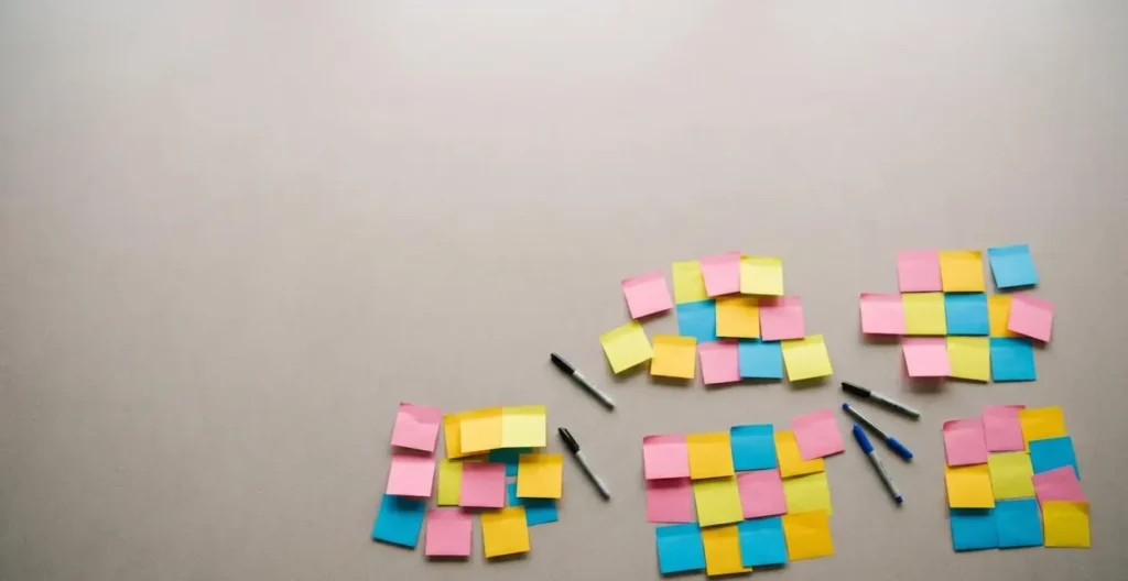 Overhead view of a conference table with scattered colorful sticky notes in soft natural light, suggesting post-workshop abandonment. Overhead view of a conference table with scattered colorful sticky notes in soft natural light, suggesting post-workshop abandonment.